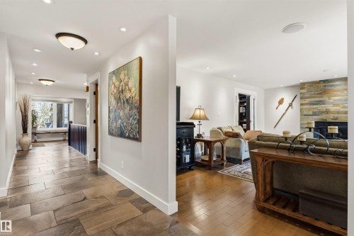 Open-concept living space featuring wood-finish flooring and a stone-clad fireplace - 9010 120 Street, Edmonton, AB - Indoor Photo Showing Other Room