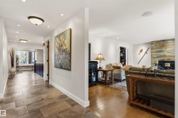 Open-concept living space featuring wood-finish flooring and a stone-clad fireplace - 