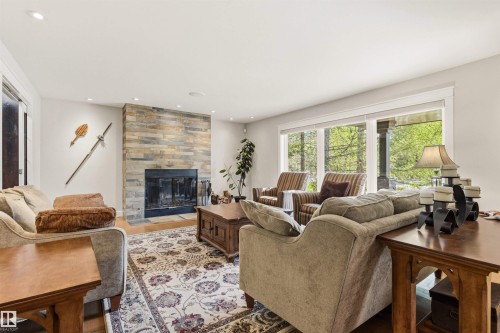 Spacious living area featuring a stone-clad fireplace and large windows - 9010 120 Street, Edmonton, AB - Indoor Photo Showing Living Room With Fireplace