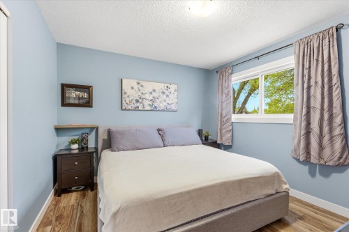Interior room featuring wood-finish flooring, a window with exterior tree canopy, and a ceiling-mounted light fixture - 111 Grosvenor Boulevard, St. Albert, AB - Indoor Photo Showing Bedroom