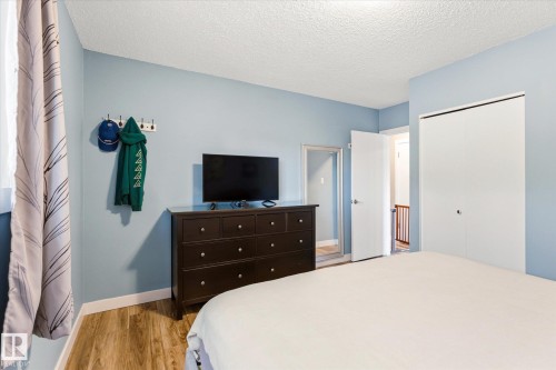 Bedroom with wood-finish flooring, light blue walls, and a white popcorn ceiling - 111 Grosvenor Boulevard, St. Albert, AB - Indoor Photo Showing Bedroom