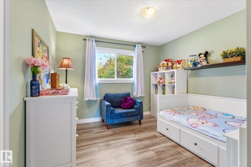 Bedroom featuring wood-finish flooring, light green walls, and a window with white trim - 111 Grosvenor Boulevard, St. Albert, AB - Indoor Photo Showing Bedroom