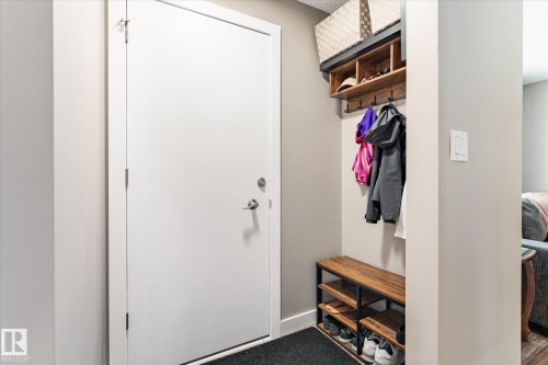 Entryway featuring a solid white door, a built-in wood-finish shelving unit, black coat hooks, and a wood-finish shoe bench with metal framing - 111 Grosvenor Boulevard, St. Albert, AB - Indoor Photo Showing Other Room