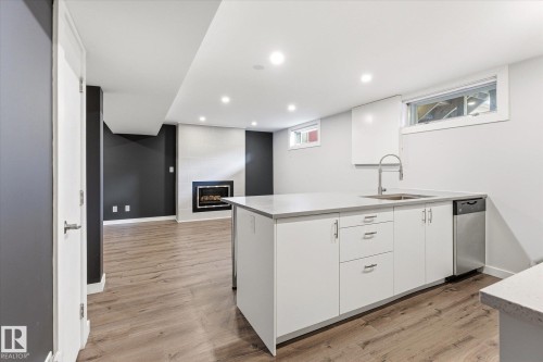 Kitchen island with a stainless steel sink, gooseneck faucet, and integrated dishwasher - 111 Grosvenor Boulevard, St. Albert, AB - Indoor