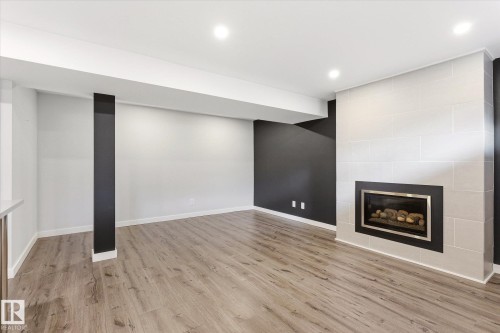 Contemporary fireplace with a black framed insert, light-colored tile surround, and wood-finish flooring - 111 Grosvenor Boulevard, St. Albert, AB - Indoor With Fireplace