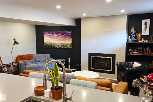 Open-concept living space with recessed lighting and a contemporary fireplace featuring a light-toned tile surround with a sleek black and chrome insert - 111 Grosvenor Boulevard, St. Albert, AB - Indoor With Fireplace