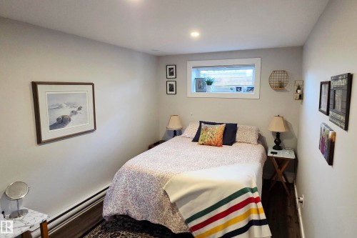 Cozy interior space featuring recessed lighting, a horizontal window with white trim, light gray walls, dark wood-finish flooring, and white baseboard heating - 111 Grosvenor Boulevard, St. Albert, AB - Indoor Photo Showing Bedroom