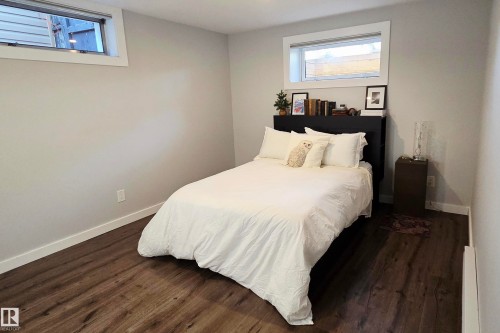 Bedroom featuring neutral gray walls, dark wood-finish flooring, white baseboards, and two transom windows - 111 Grosvenor Boulevard, St. Albert, AB - Indoor Photo Showing Bedroom
