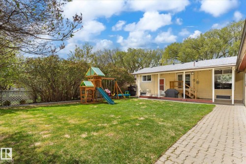 Expansive backyard with a manicured lawn, established perimeter landscaping, and a paved patio area - 111 Grosvenor Boulevard, St. Albert, AB - Outdoor With Deck Patio Veranda