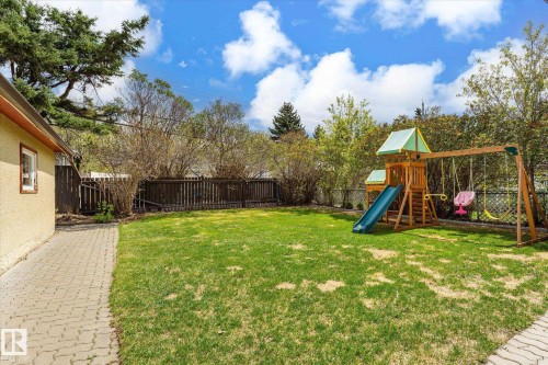 Expansive backyard featuring a green lawn, mature trees, and a full perimeter fence - 111 Grosvenor Boulevard, St. Albert, AB - Outdoor