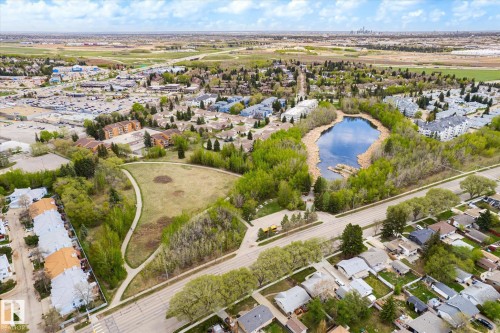 Aerial perspective showcasing a residential area with a prominent central pond surrounded by mature trees - 111 Grosvenor Boulevard, St. Albert, AB - Outdoor With View