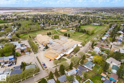 Aerial neighborhood perspective featuring extensive green spaces, a large institutional building with substantial parking, and a body of water in the background - 111 Grosvenor Boulevard, St. Albert, AB - Outdoor With View