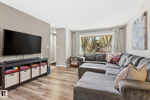 Living space featuring wood-finish flooring, neutral wall tones, and a large window providing natural light - 111 Grosvenor Boulevard, St. Albert, AB - Indoor Photo Showing Living Room