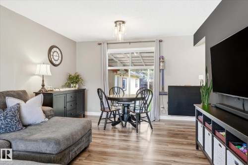 Open-concept living space featuring wood-finish flooring, a dining area with a window, and a modern ceiling light fixture - 111 Grosvenor Boulevard, St. Albert, AB - Indoor