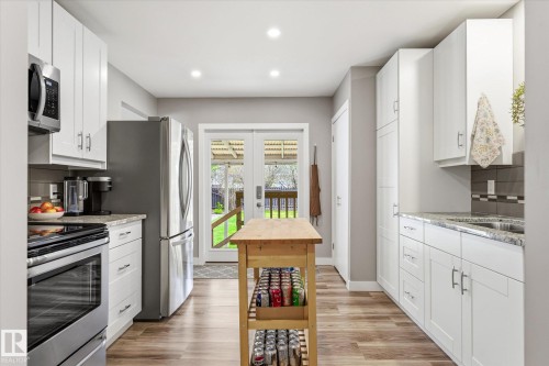 Modern kitchen featuring white cabinetry, stainless steel appliances, wood-finish flooring, and recessed lighting - 111 Grosvenor Boulevard, St. Albert, AB - Indoor Photo Showing Kitchen With Stainless Steel Kitchen