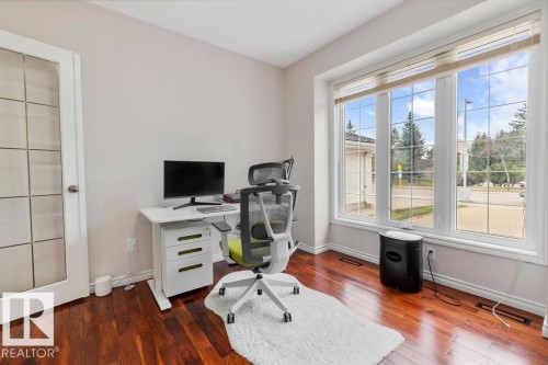 Bright room featuring expansive windows, rich wood-finish flooring, white baseboards, and a glass-paneled door - 956 Ogilvie Boulevard, Edmonton, AB - Indoor Photo Showing Office