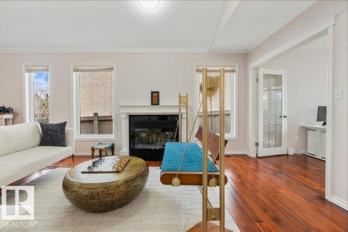 Bright living area featuring a fireplace with a white mantel, hardwood flooring, and multiple windows - 956 Ogilvie Boulevard, Edmonton, AB - Indoor Photo Showing Living Room With Fireplace