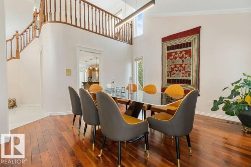 Two-story dining space featuring hardwood flooring, a curved architectural wall, a recessed window, and a linear overhead light fixture - 956 Ogilvie Boulevard, Edmonton, AB - Indoor Photo Showing Dining Room