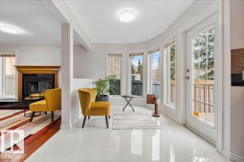 Bright interior featuring white tile flooring, large windows, a glass-paned door, a wooden fireplace mantel, and recessed lighting - 956 Ogilvie Boulevard, Edmonton, AB - Indoor With Fireplace