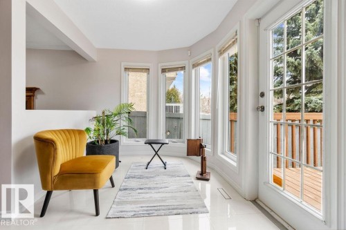 Sunlit interior space featuring white tile flooring, a large patio door with grid patterns, and multiple bay windows - 956 Ogilvie Boulevard, Edmonton, AB - Indoor Photo Showing Other Room