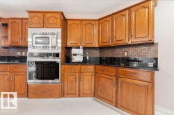 Kitchen with wood cabinetry, black countertops, and a mosaic tile backsplash - 