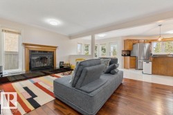 Living area with wood-finish flooring, a fireplace featuring a dark stone surround and hearth, and a wood mantel - 