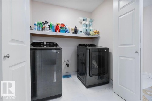 Dedicated laundry area featuring white tile flooring and a wall-mounted shelving unit - 956 Ogilvie Boulevard, Edmonton, AB - Indoor Photo Showing Laundry Room