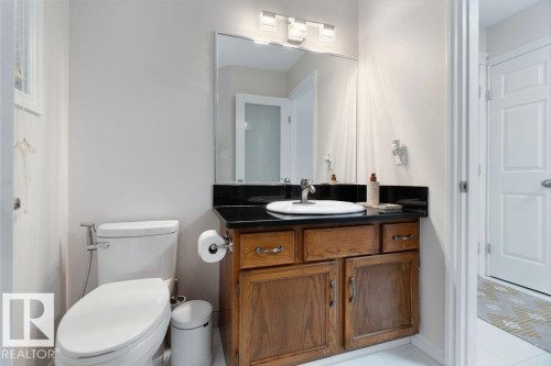 Vanity featuring a dark countertop, white oval sink, and wood cabinetry - 956 Ogilvie Boulevard, Edmonton, AB - Indoor Photo Showing Bathroom
