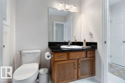 Vanity featuring a dark countertop, white oval sink, and wood cabinetry - 