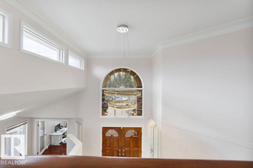 Two-story foyer featuring an arched window, double-door entry, a contemporary multi-tier chandelier, and crown molding - 956 Ogilvie Boulevard, Edmonton, AB - Indoor Photo Showing Other Room