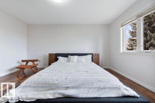 Bright interior space featuring wood-finish flooring, a contemporary window, and a modern ceiling light fixture - 956 Ogilvie Boulevard, Edmonton, AB - Indoor Photo Showing Bedroom