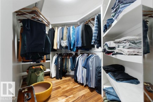 Custom closet system featuring wood-finish flooring, white shelving, and multiple hanging rods - 956 Ogilvie Boulevard, Edmonton, AB - Indoor With Storage