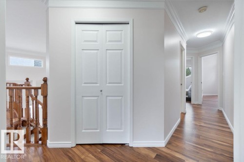 Hallway featuring wood-finish flooring, crisp white walls, crown molding, a paneled bi-fold door, and recessed lighting - 956 Ogilvie Boulevard, Edmonton, AB - Indoor Photo Showing Other Room