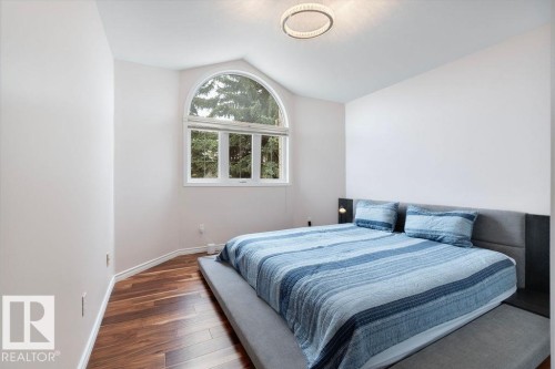 Room featuring a large arched window, wood-finish flooring, and a contemporary ceiling fixture - 956 Ogilvie Boulevard, Edmonton, AB - Indoor Photo Showing Bedroom