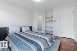 Bedroom featuring wood-finish flooring, a white six-panel door, and built-in shelving - 