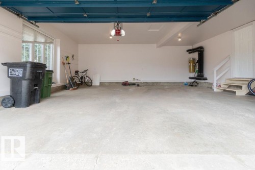 Spacious garage featuring a concrete floor, white painted walls, and a painted overhead garage door system - 956 Ogilvie Boulevard, Edmonton, AB - Indoor Photo Showing Garage