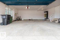 Spacious garage featuring a concrete floor, white painted walls, and a painted overhead garage door system - 
