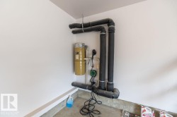 Utility area featuring a central vacuum system, insulated piping, and a dedicated electrical outlet - 