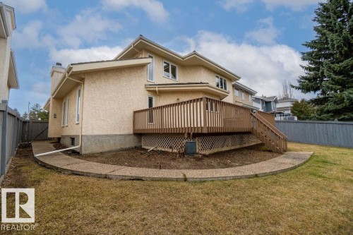 Rear exterior featuring a spacious wood-finish deck with stairs to the yard, stucco siding, and a concrete pathway - 956 Ogilvie Boulevard, Edmonton, AB - Outdoor
