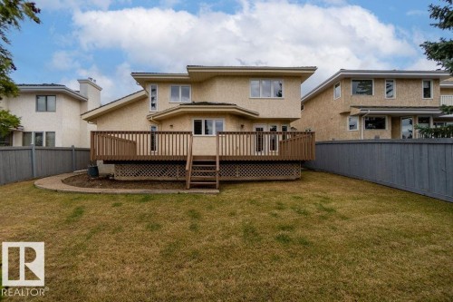 Rear exterior featuring an elevated wood deck with railing and stairs, multiple windows, French doors, and stucco siding - 956 Ogilvie Boulevard, Edmonton, AB - Outdoor With Deck Patio Veranda