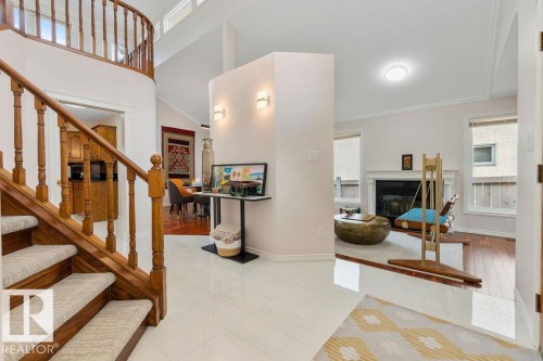 Foyer showcasing white tile flooring, a curved wood staircase with carpeted treads, and a partial wall with sconce lighting - 956 Ogilvie Boulevard, Edmonton, AB - Indoor Photo Showing Other Room