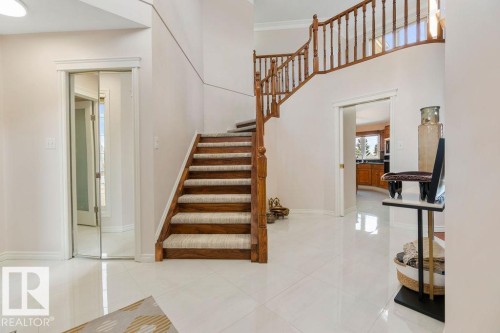 Grand foyer featuring a curved staircase with natural wood banister, white tile flooring, and neutral wall tones - 956 Ogilvie Boulevard, Edmonton, AB - Indoor Photo Showing Other Room