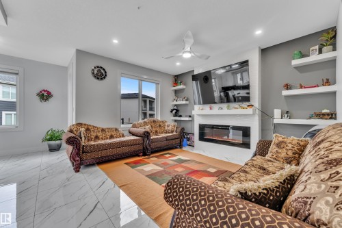 Living area featuring large format white tile flooring, a built-in electric fireplace with white surround, recessed lighting, and a modern ceiling fan - 1827 22 Street Nw, Edmonton, AB - Indoor Photo Showing Living Room With Fireplace