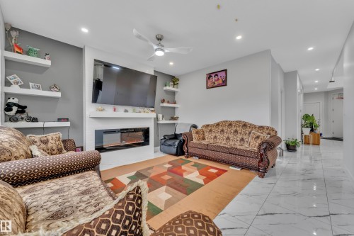 Living area featuring a modern electric fireplace with a white surround and built-in floating shelves - 1827 22 Street Nw, Edmonton, AB - Indoor Photo Showing Living Room With Fireplace