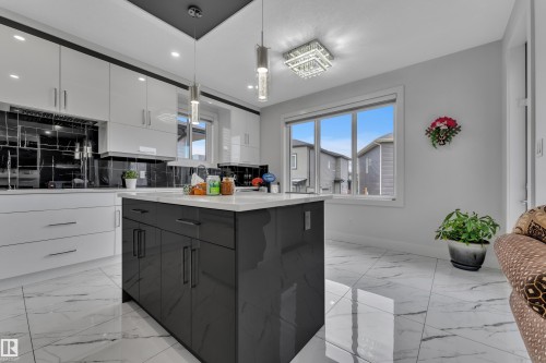 Modern kitchen featuring a central island with dark cabinetry and a light countertop, complemented by white upper and lower cabinetry - 1827 22 Street Nw, Edmonton, AB - Indoor Photo Showing Kitchen