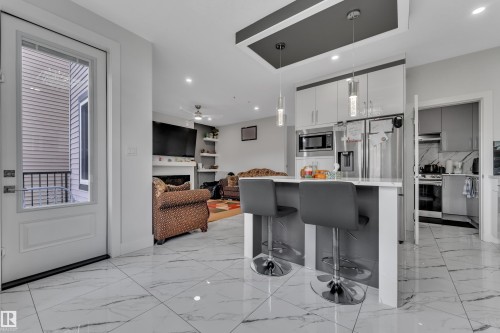 Open-concept living space featuring large format marble-look tile flooring, a kitchen island with seating, stainless steel appliances, and recessed lighting - 1827 22 Street Nw, Edmonton, AB - Indoor Photo Showing Kitchen With Upgraded Kitchen