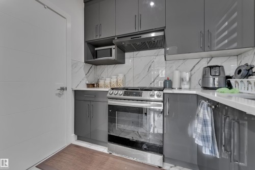 Modern kitchen featuring sleek gray cabinetry, a stainless steel range, and a coordinating range hood - 1827 22 Street Nw, Edmonton, AB - Indoor Photo Showing Kitchen