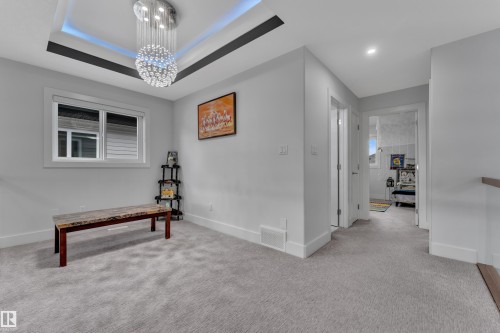 Carpeted landing area featuring a contemporary crystal chandelier, recessed ceiling lighting, a window with white trim, and white baseboards - 1827 22 Street Nw, Edmonton, AB - Indoor Photo Showing Other Room