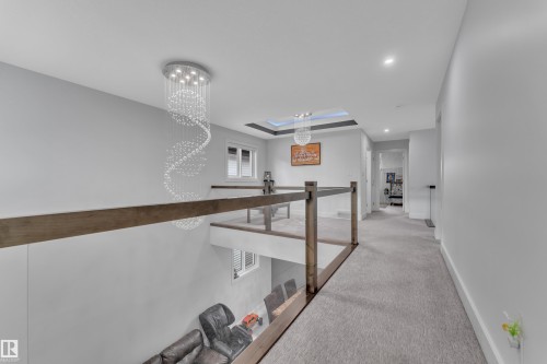 Upper-level hallway featuring a striking spiral crystal chandelier, recessed lighting, and light gray carpeting - 1827 22 Street Nw, Edmonton, AB - Indoor Photo Showing Other Room