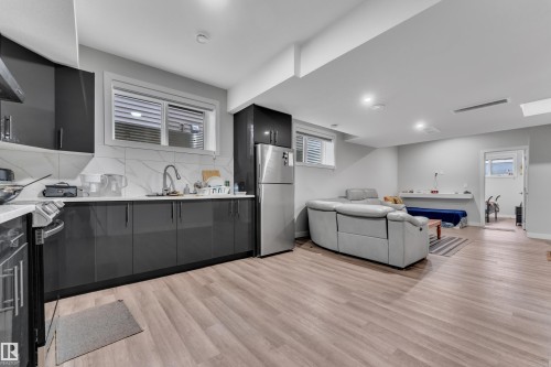 Kitchenette featuring dark cabinetry, stainless steel appliances, a white countertop, and a white tile backsplash - 1827 22 Street Nw, Edmonton, AB - Indoor